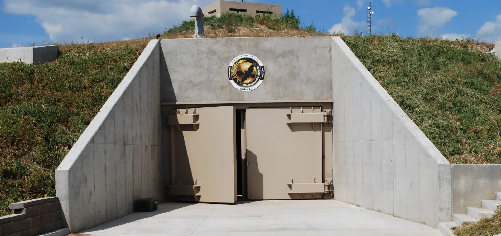 A large concrete building with two doors and a bell on the top.