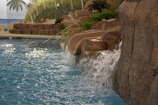 A pool with water slides and rocks in it